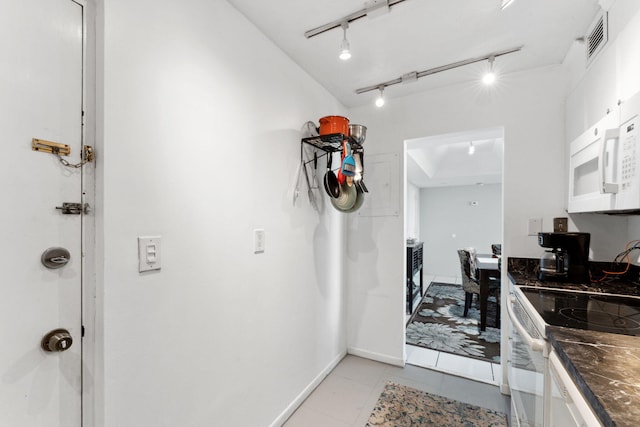 kitchen with white appliances, light tile patterned floors, baseboards, visible vents, and dark countertops