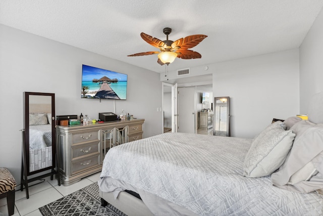 bedroom featuring light tile patterned floors, ceiling fan, visible vents, and a textured ceiling