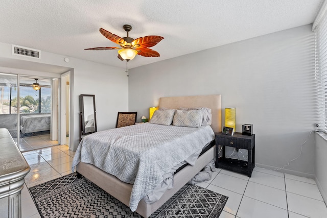 bedroom with a textured ceiling, light tile patterned flooring, a ceiling fan, visible vents, and access to exterior