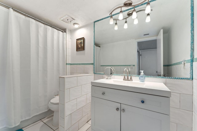 full bath featuring a wainscoted wall, tile walls, visible vents, toilet, and vanity