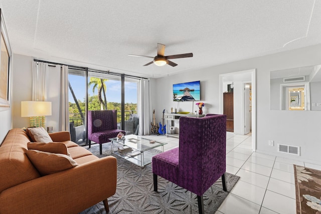 living area featuring light tile patterned floors, ceiling fan, a textured ceiling, visible vents, and a wall of windows