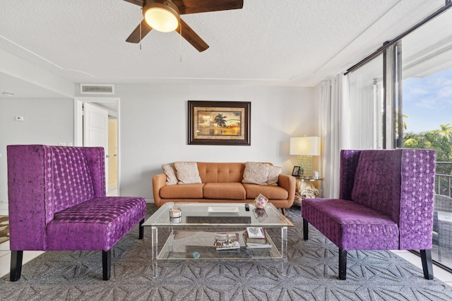 living room with ceiling fan, visible vents, and a textured ceiling