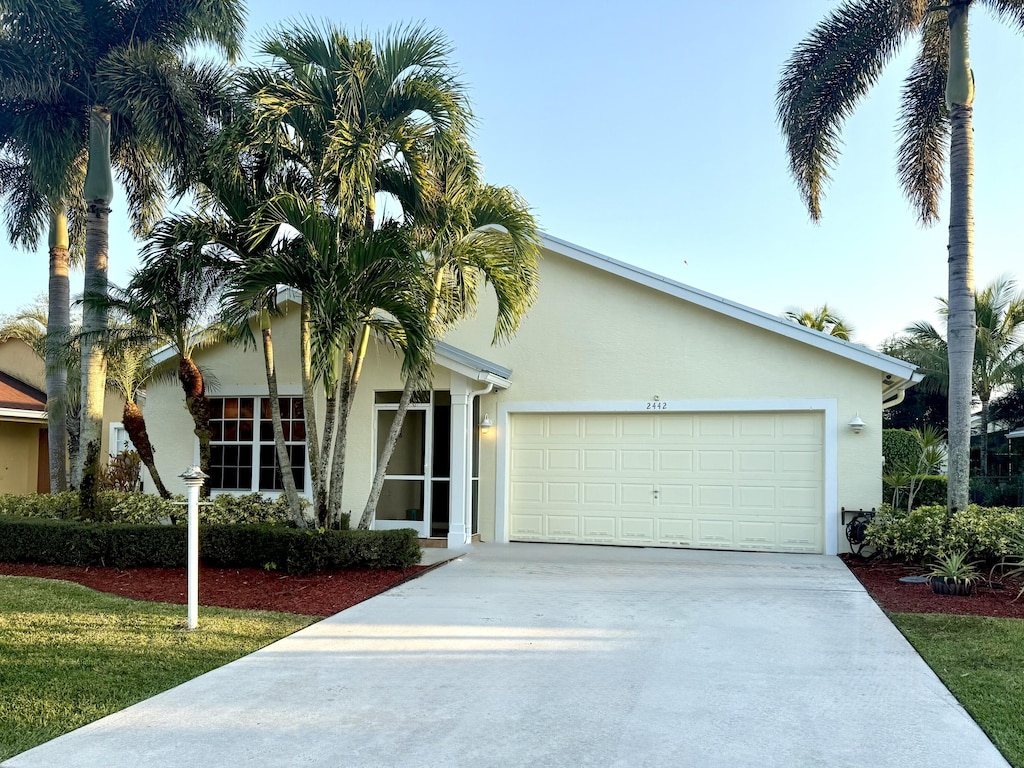 ranch-style home with concrete driveway, an attached garage, and stucco siding