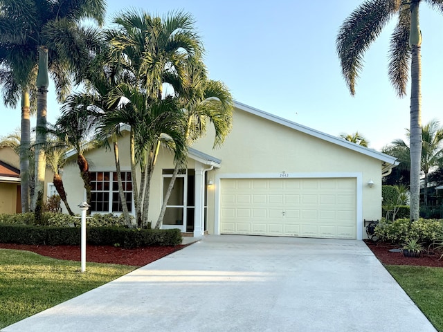 ranch-style home with concrete driveway, an attached garage, and stucco siding