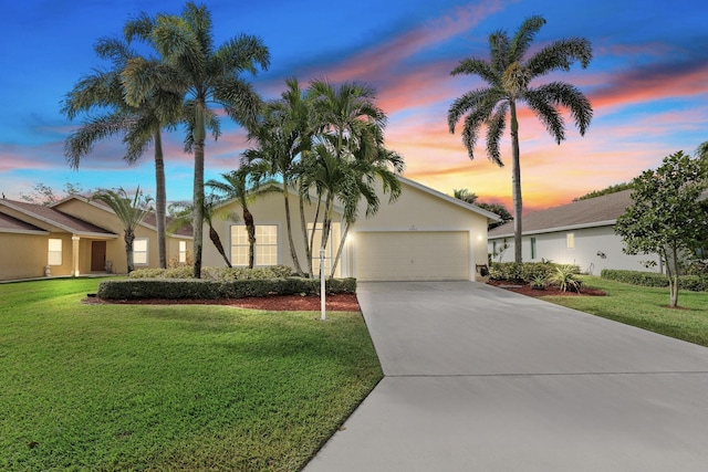 view of front facade with a front yard, driveway, an attached garage, and stucco siding