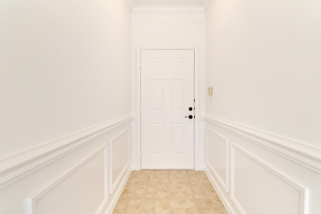 entryway with light tile patterned floors, a decorative wall, crown molding, and wainscoting