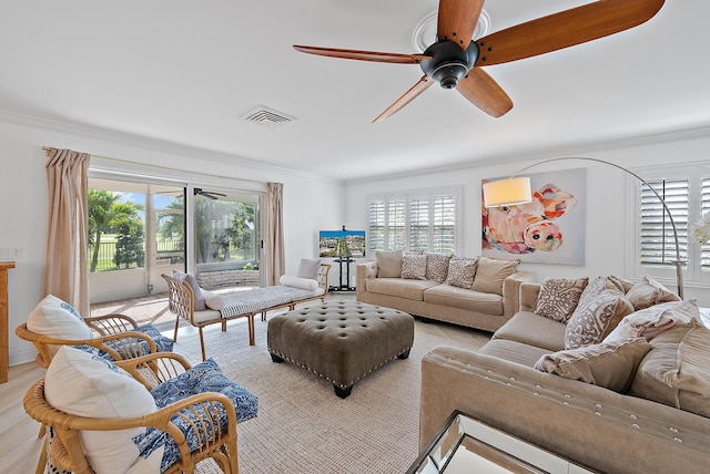 living area featuring light wood-type flooring, a ceiling fan, visible vents, and crown molding