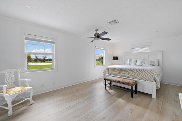 bedroom featuring visible vents, light wood-style flooring, a ceiling fan, a textured ceiling, and baseboards