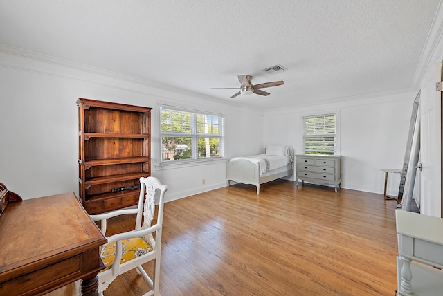 bedroom with a textured ceiling, visible vents, baseboards, light wood-style floors, and crown molding