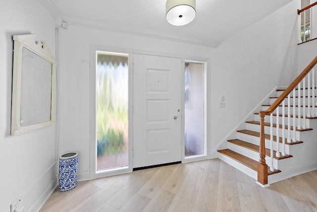 entrance foyer with baseboards, stairway, wood finished floors, and ornamental molding