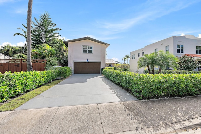 view of front facade with a garage, driveway, and fence