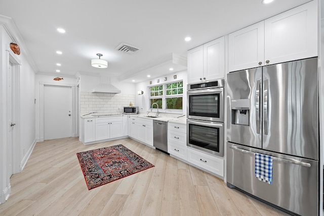 kitchen featuring white cabinets, tasteful backsplash, stainless steel appliances, and light wood-style flooring