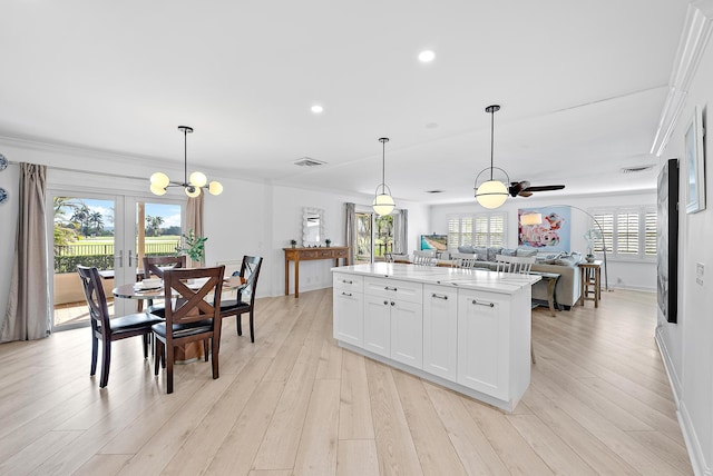 kitchen with hanging light fixtures, light wood-style flooring, white cabinetry, and a center island