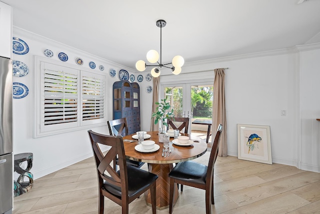 dining space featuring a chandelier, light wood finished floors, baseboards, and crown molding