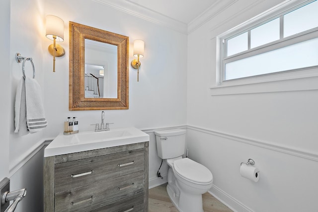 bathroom featuring baseboards, crown molding, vanity, and toilet