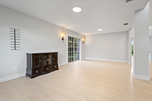 unfurnished living room with a healthy amount of sunlight, light wood-style floors, visible vents, and baseboards