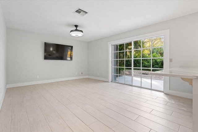 spare room with light wood finished floors, baseboards, and visible vents