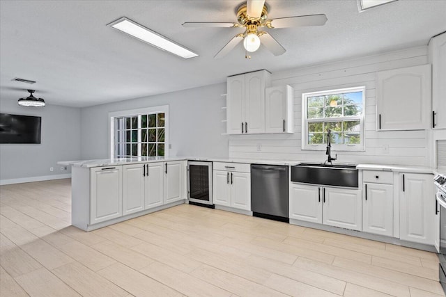 kitchen with beverage cooler, a peninsula, a sink, light countertops, and dishwasher