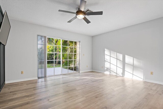 unfurnished living room with a ceiling fan, a textured ceiling, baseboards, and wood finished floors