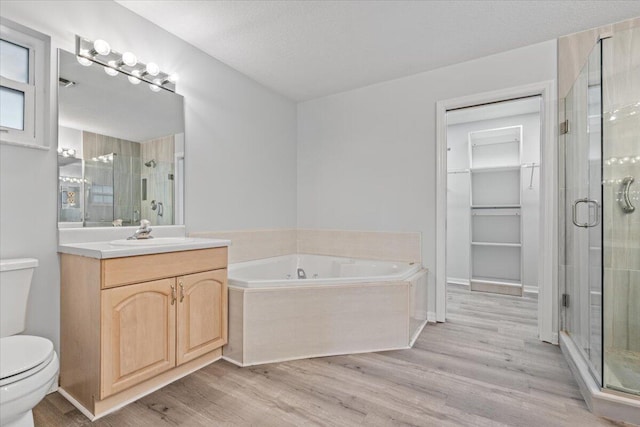 full bath with a stall shower, vanity, toilet, and wood finished floors