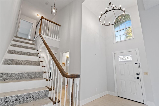 entrance foyer featuring stairs, a towering ceiling, baseboards, and wood finished floors