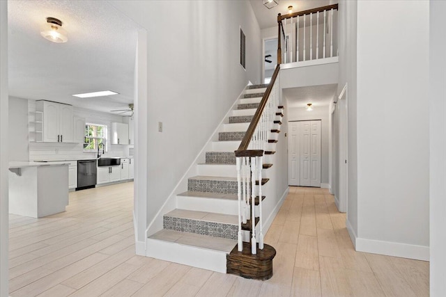 stairs featuring ceiling fan, baseboards, and wood finished floors