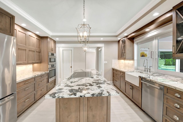 kitchen featuring stainless steel appliances, a raised ceiling, a sink, and a kitchen island