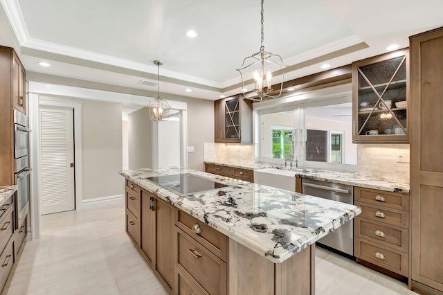 kitchen featuring visible vents, a raised ceiling, a kitchen island, glass insert cabinets, and stainless steel appliances