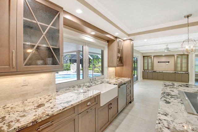 kitchen featuring decorative backsplash, dishwasher, hanging light fixtures, light stone countertops, and a sink