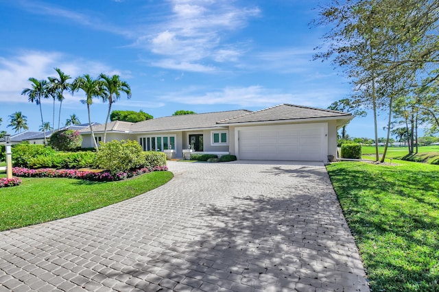 ranch-style home featuring a garage, a tile roof, decorative driveway, a front lawn, and stucco siding