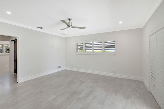 empty room featuring a ceiling fan, visible vents, baseboards, and a barn door