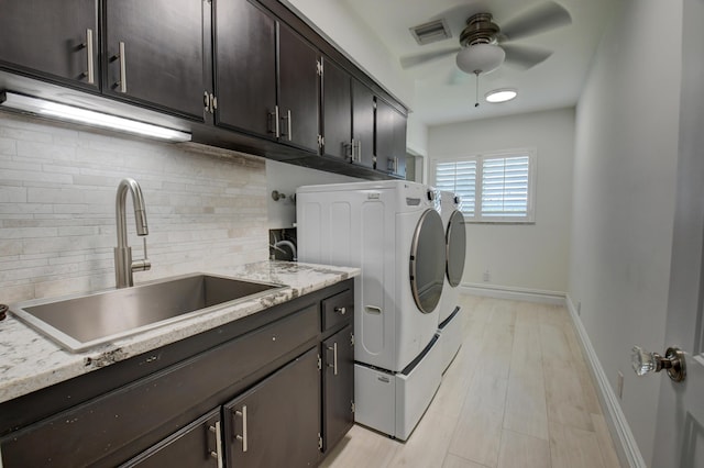 washroom with cabinet space, baseboards, visible vents, washer and dryer, and a sink