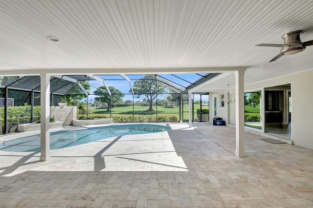 outdoor pool with glass enclosure, a patio area, and a ceiling fan