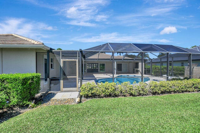 rear view of house featuring a lanai, a tiled roof, a lawn, an outdoor pool, and stucco siding