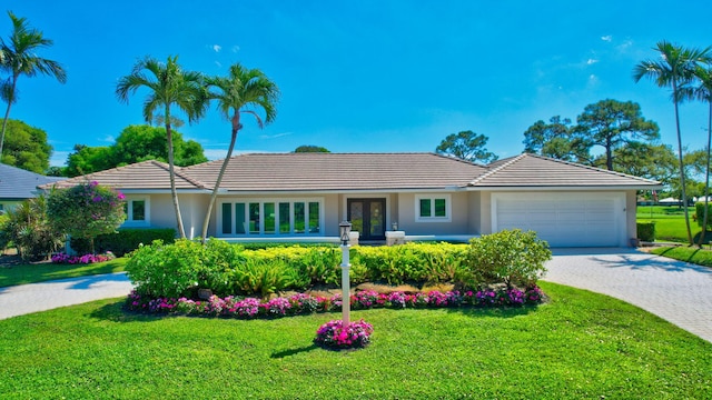 ranch-style house with a garage, a tiled roof, decorative driveway, stucco siding, and a front yard