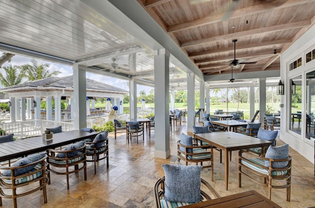 sunroom / solarium with wood ceiling, beamed ceiling, and ceiling fan