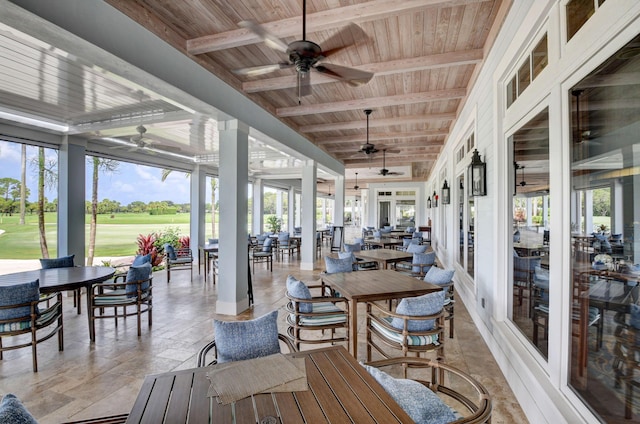 sunroom / solarium featuring beam ceiling, wood ceiling, and a ceiling fan