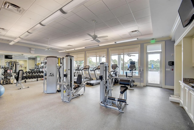 exercise room with ornamental molding, a tray ceiling, visible vents, and a ceiling fan