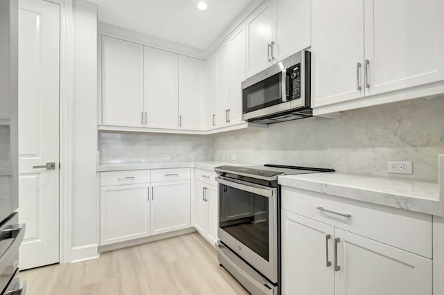 kitchen featuring white cabinets, light wood-style floors, tasteful backsplash, and stainless steel appliances