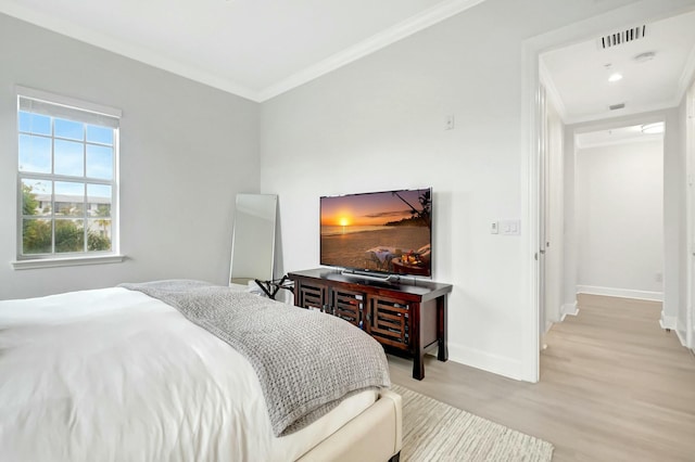 bedroom with light wood-type flooring, visible vents, crown molding, and baseboards