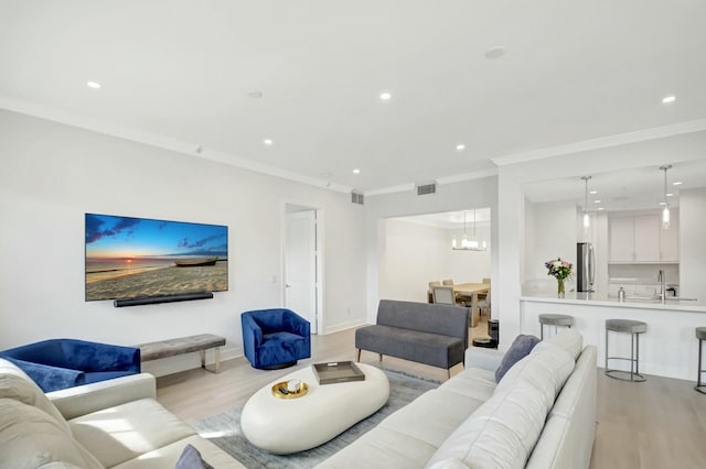 living room featuring ornamental molding, recessed lighting, and light wood finished floors