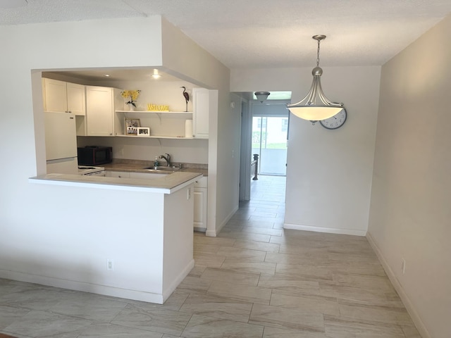 kitchen with black microwave, a sink, white cabinetry, freestanding refrigerator, and open shelves