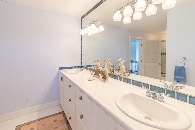 full bath featuring double vanity, baseboards, and a sink