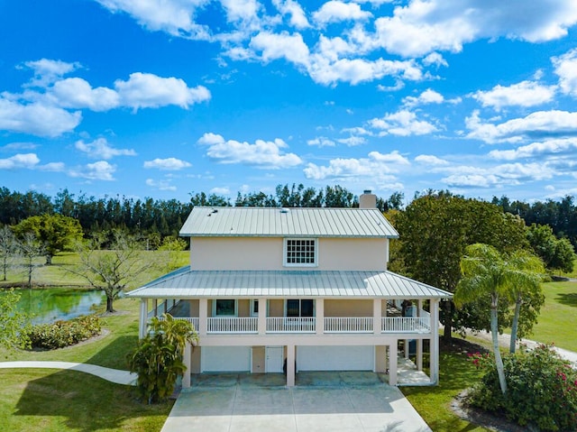 view of front of house with a chimney, metal roof, a standing seam roof, a front lawn, and stucco siding