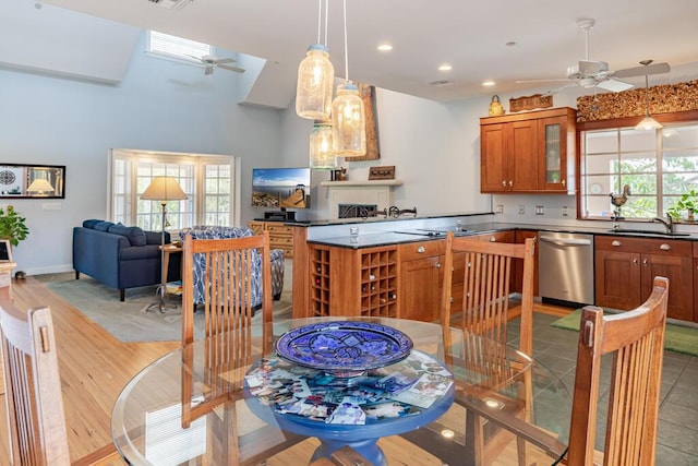 kitchen with a sink, a healthy amount of sunlight, stainless steel dishwasher, brown cabinetry, and glass insert cabinets