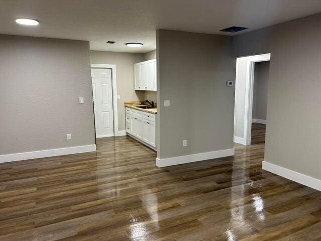 interior space featuring dark wood-style floors, baseboards, visible vents, and a sink