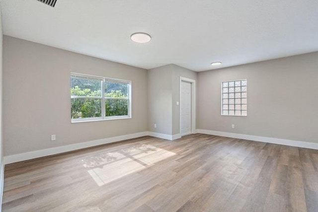 empty room with plenty of natural light, baseboards, and wood finished floors