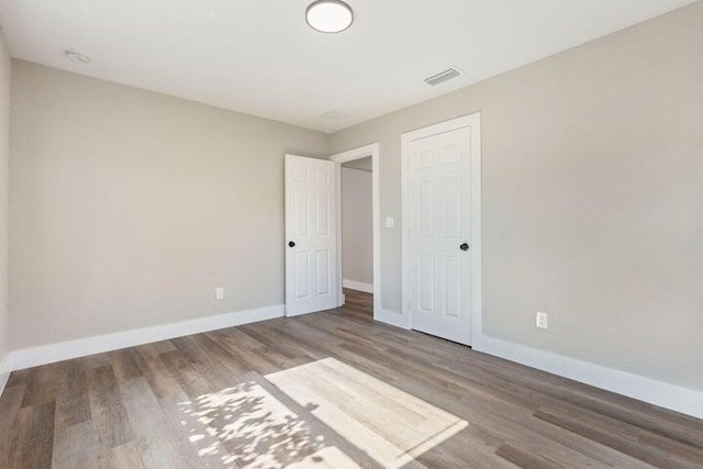 unfurnished bedroom with visible vents, baseboards, and wood finished floors