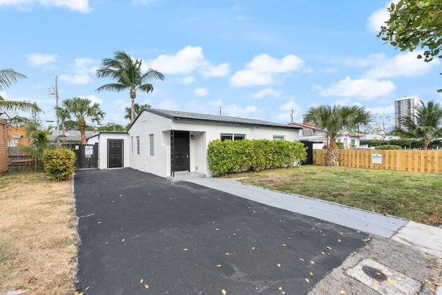 view of front of house featuring fence, a front lawn, and stucco siding