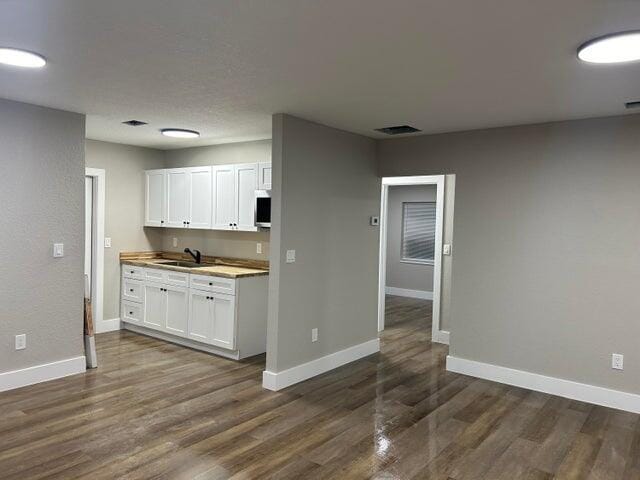 kitchen featuring white cabinetry, visible vents, dark wood finished floors, and baseboards